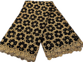 Black and gold floral lace fabric on a white marble surface