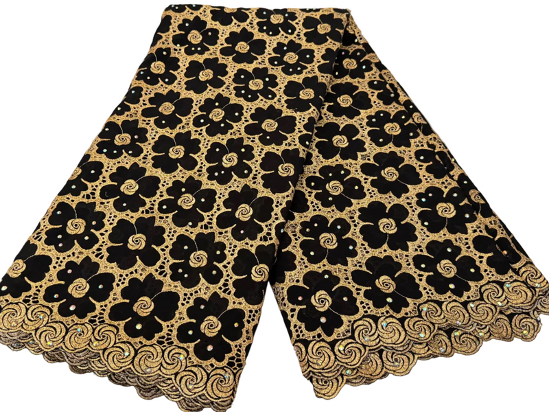 Black and gold floral lace fabric on a white marble surface