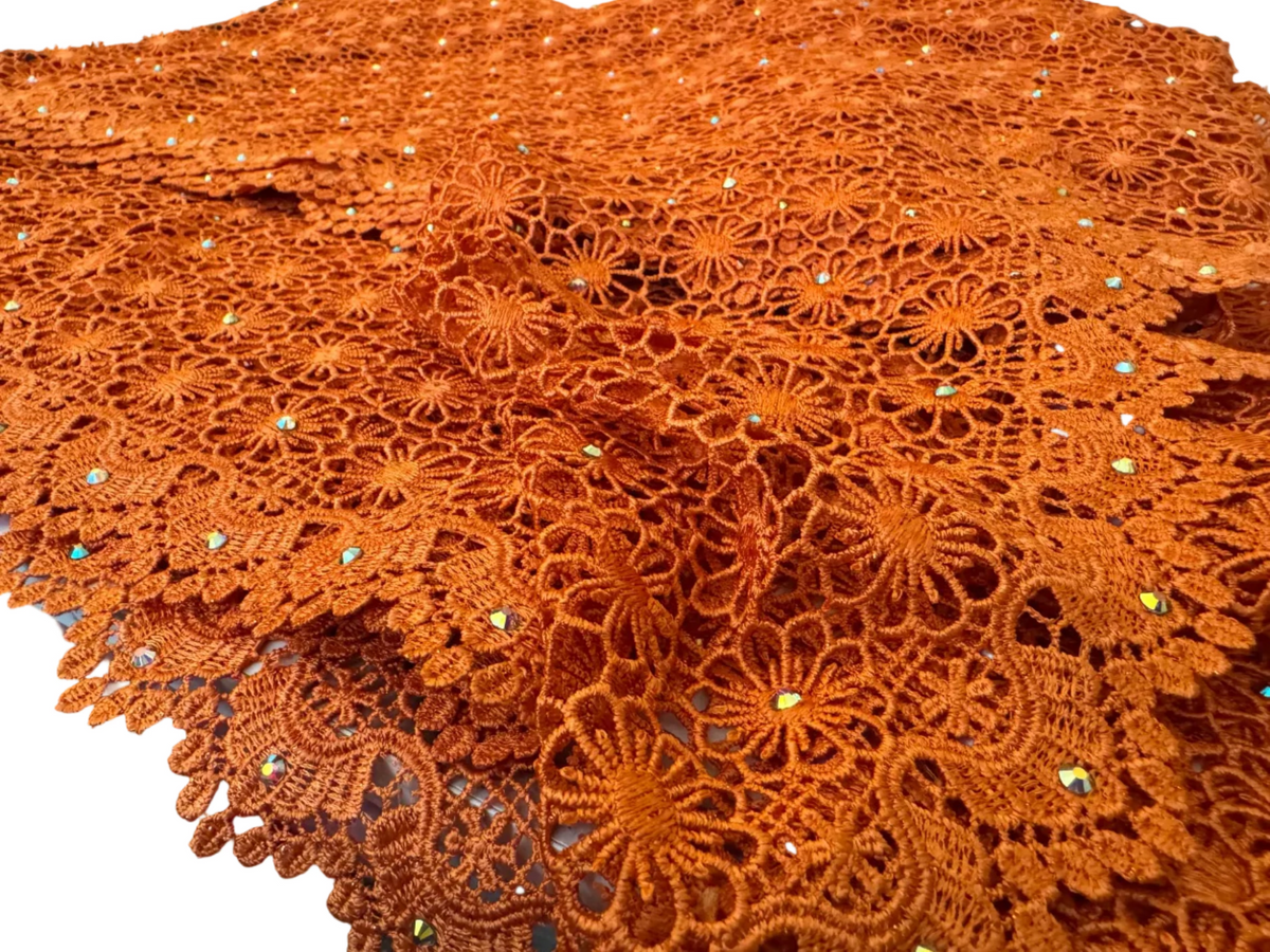 Orange lace tablecloth with bead embellishments on a table.