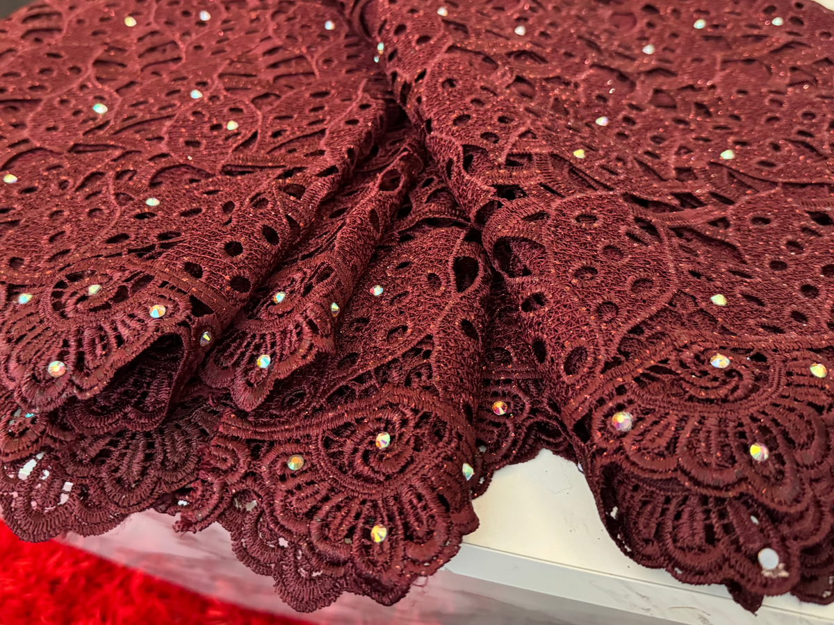 Wine lace fabric with embellishments on a white surface